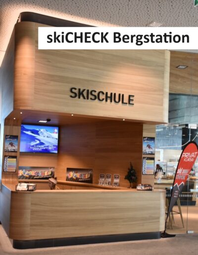 Skischul-Schalter von skiCHECK an der Bergstation mit Holzverkleidung und Infobildschirm
