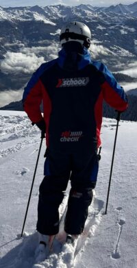 skiCHECK-Skilehrer von hinten im Tiefschnee mit Blick auf die Berge