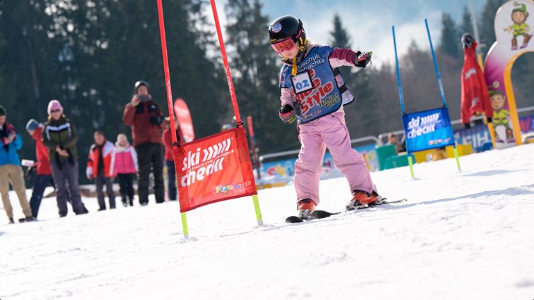 Kind mit Helm und Startnummer fährt beim skiCHECK-Kinderrennen durch ein Slalomtor